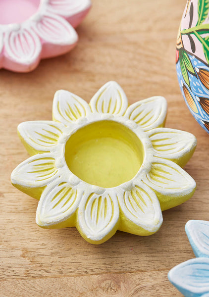 Flower-shaped ceramic candle holder on a wooden surface